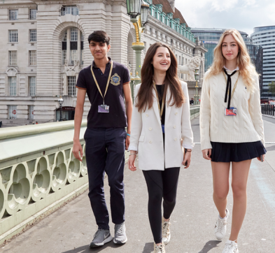 Students Walkinga Cross Westminster Bridge In London With DLD College London In The Background