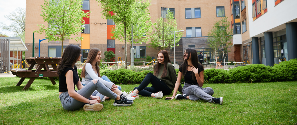 Students at ACC sitting outside in the lawn.