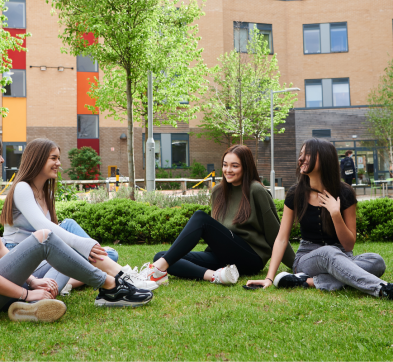 Students at ACC sitting outside in the lawn.